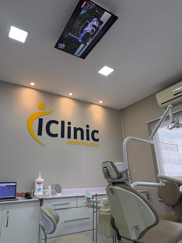 Consultório da iClinic com o logotipo na parede e a cadeira odontológica